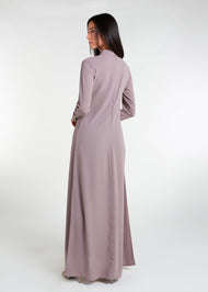 This Box Pleat Abaya Taupe features a fluid, A-line cut with a neat box pleat that runs from the high neck line to the bottom of the garment. The abaya is lightweight and airy, and a slip is necessary to wear underneath.