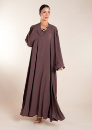 This elegant Two Piece Open Abaya set includes a Full Sleeve matching inner dress. Perfect for everyday wear, it can also be dressed up with accessories for an evening look. The open abaya can be worn as a maxi on its own or paired with the inner dress for a stylish ensemble. In brown.