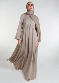 This waist pleat abaya in beige boasts a flattering fit with light pleating on the waist and bodice. Perfect for summer, the flared bell sleeves add a breezy touch, while the discreet button opening on the front of the bodice adds a thoughtful detail.