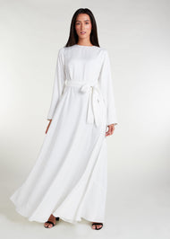 This fully lined white abaya boasts subtle pleats strategically placed at the waist to gently accentuate your figure. An optional belt is included for those who prefer a cinched waist. 